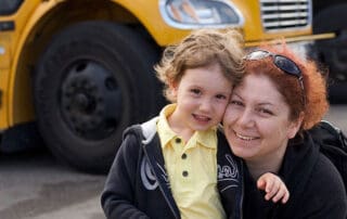 adult and child with school bus in backgournd